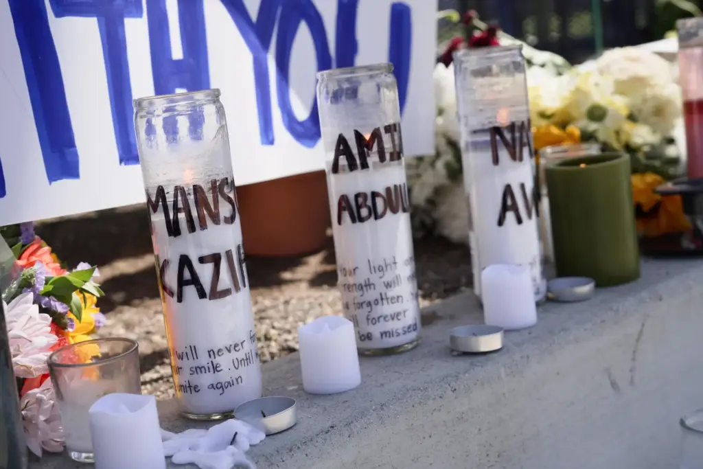 FILE – Candles with victim’s names written on them are...