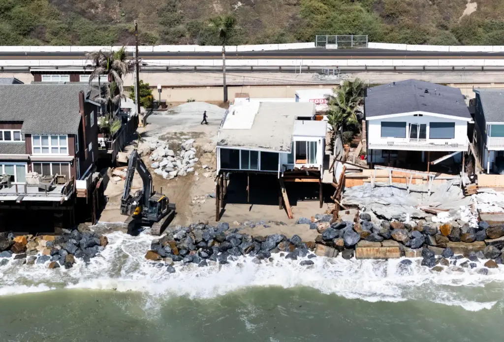 Heavy equipment moves boulders into place to protect homes along...