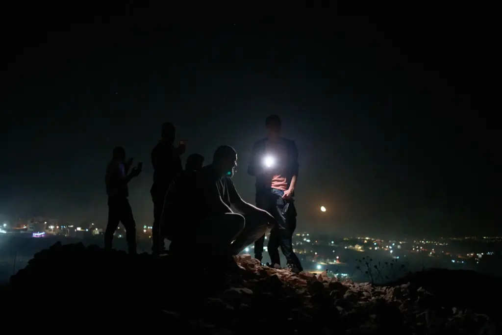 Palestinians stand atop a hill during a volunteer night watch.