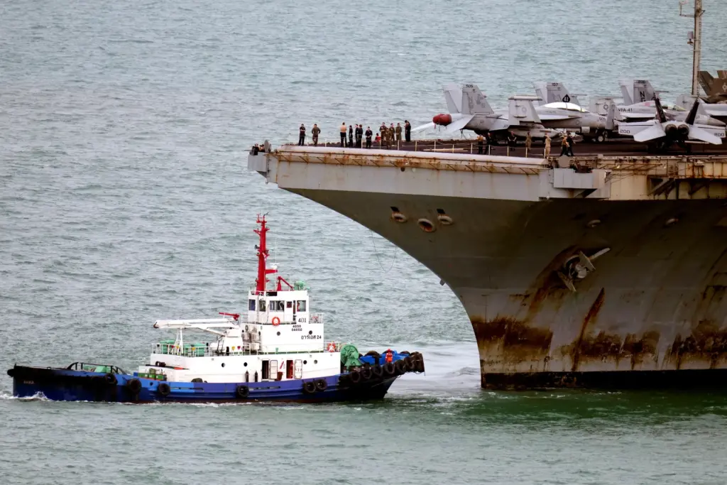 A tug boat greets the U.S. Navy aircraft carrier USS...