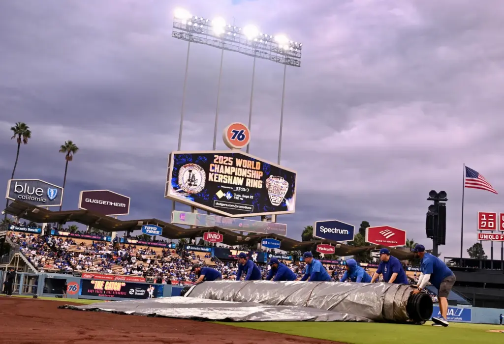 The Dodgers grounds crew rolls up the tarp before the...