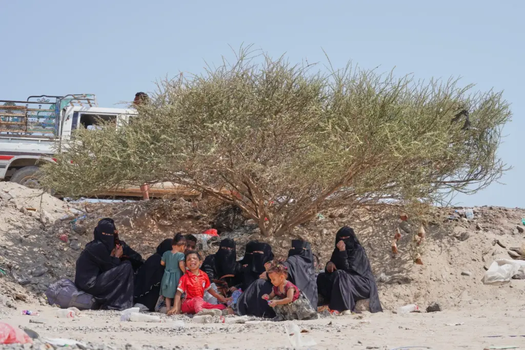 Displaced Yemenis sit outside at Al-Firdaws camp in Ras Imran.