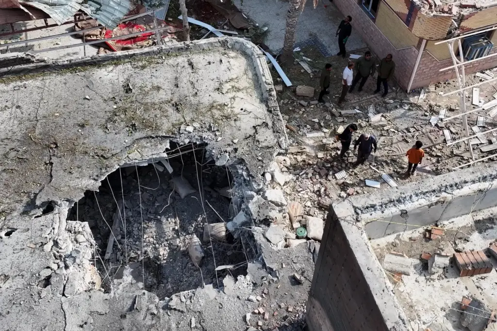 People inspect damage and debris at a building that Iranian...