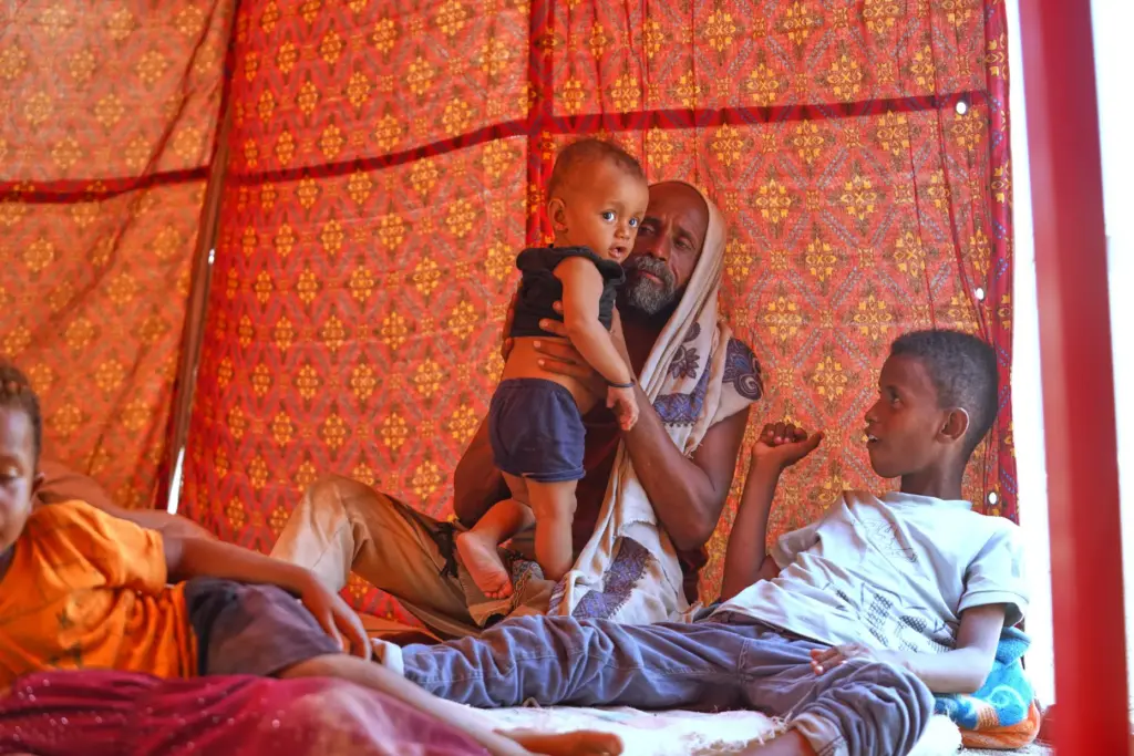 Displaced Yemenis sit at their tent at Al-Firdaws camp in Ras Imran.