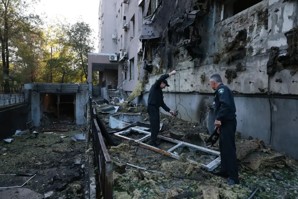 Police officers collect fragments of a drone in front of...