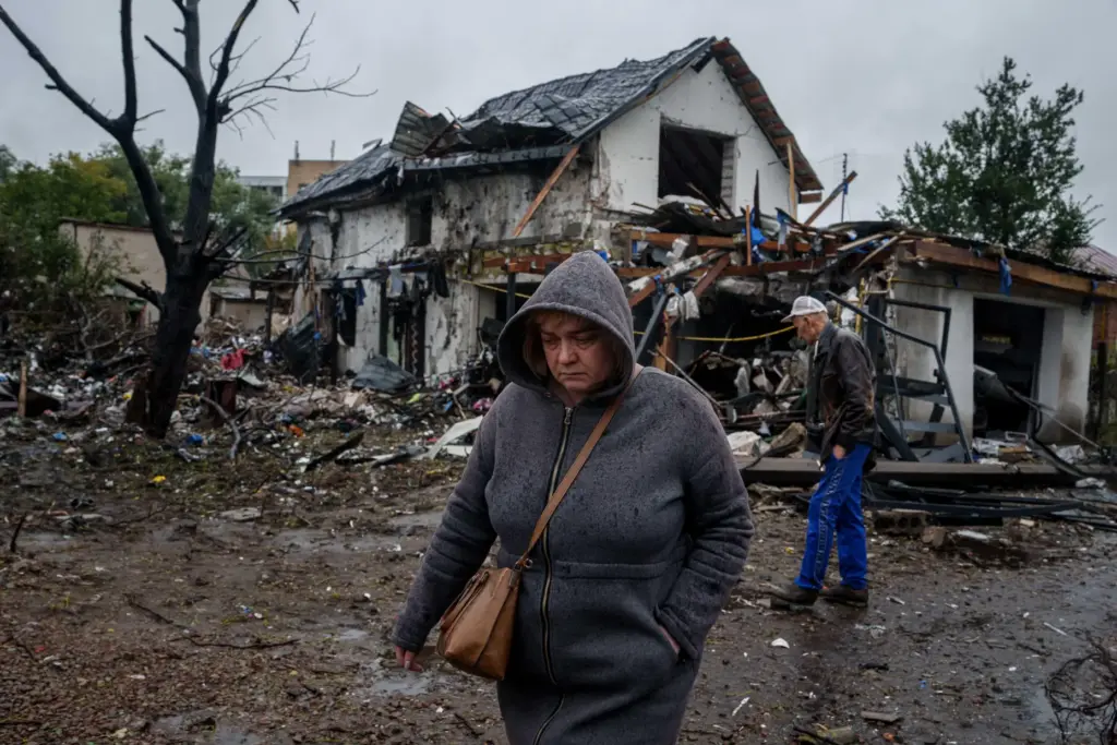 A woman walks in front of a house that was heavily damaged in a Russian strike.