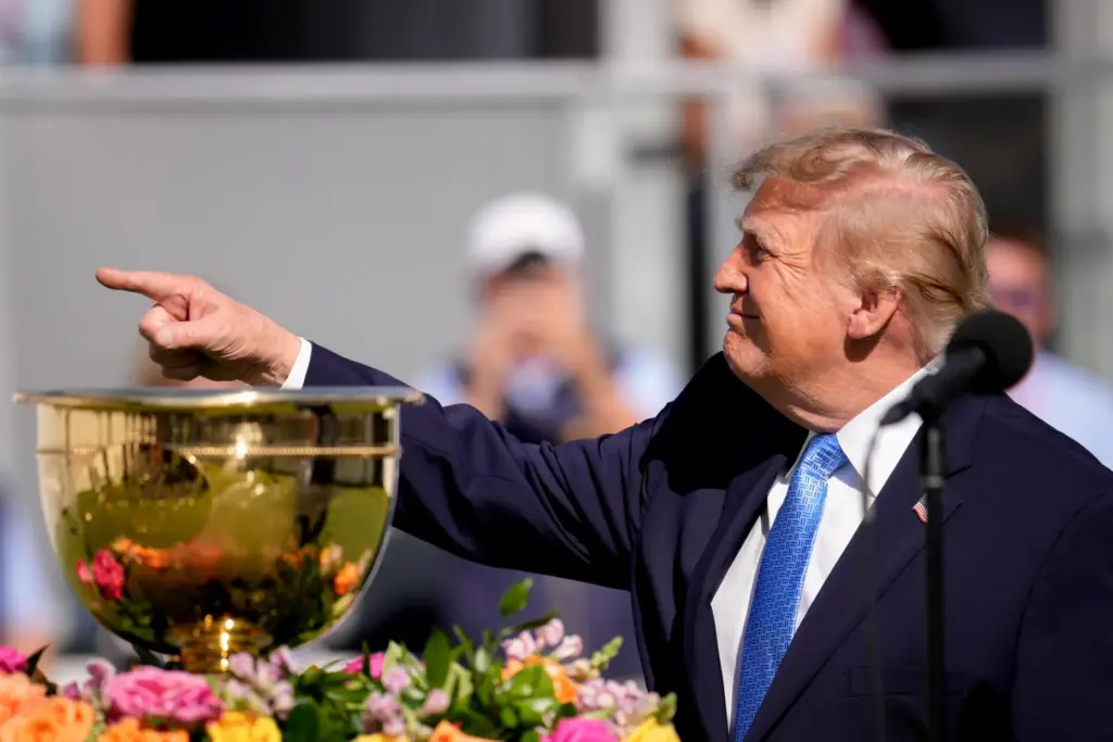President Donald Trump points towards fans from the first tee...
