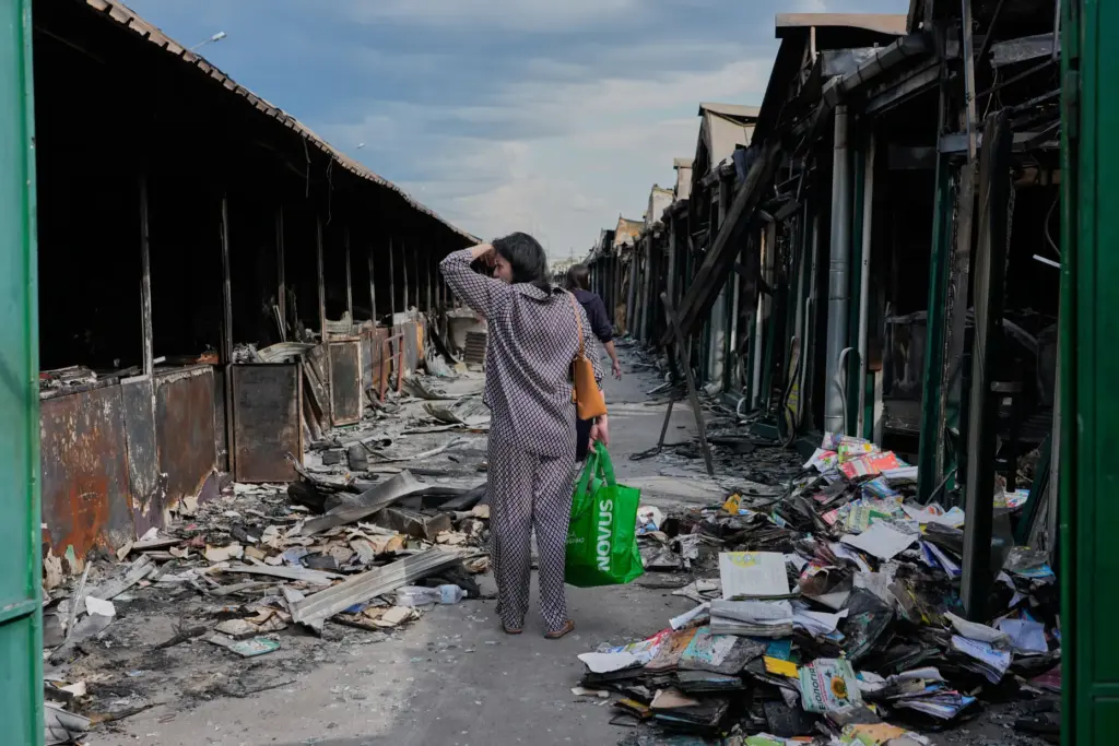FILE – A woman reacts to charred books after a...