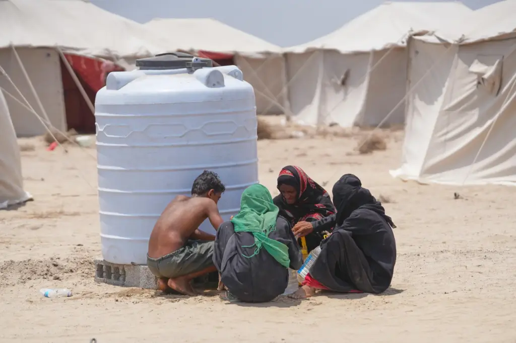 Displaced Yemenis chat at Al-Firdaws camp in Ras Imran.