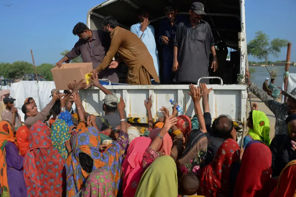 FILE – Displaced families, who fled their flood-hit homes, jostle...