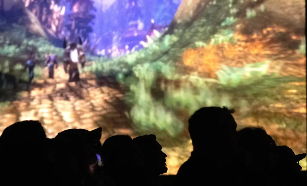 With projection screens surrounding them, Blizzard Entertainment enthusiasts watch animations...