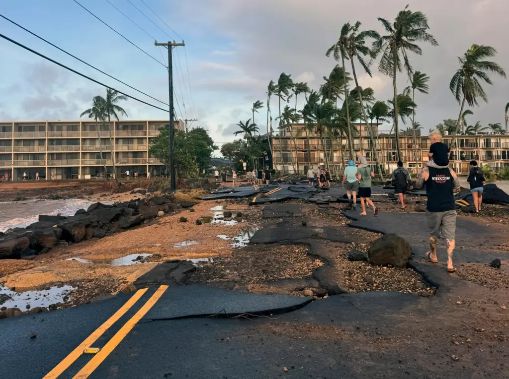 People walk past damage caused by Hurricane Lowell.