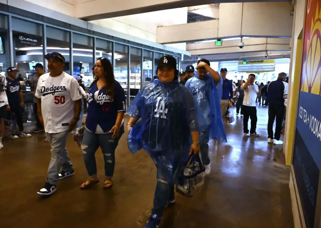 Baseball fans make their way from the rain prior to...
