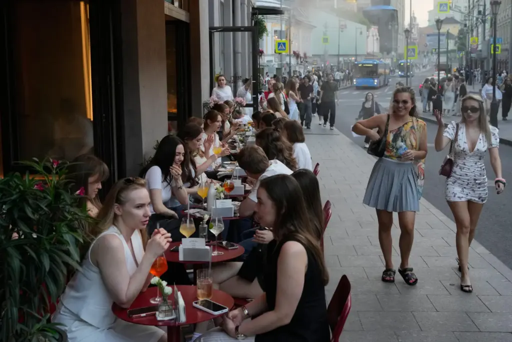 People sit at a sidewalk cafe on a hot summer day in Moscow.