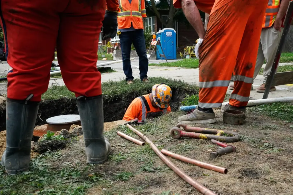 Workers install a copper pipe to replace a lead service...