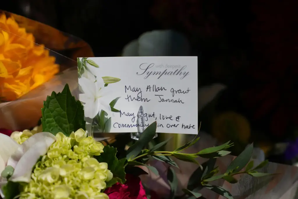 FILE – A note attached to flowers is placed outside...