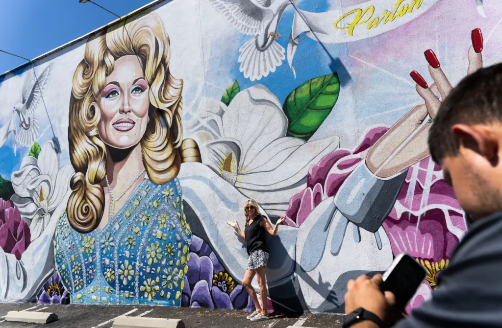 Janine Schonert takes a photo at a mural of Dolly...