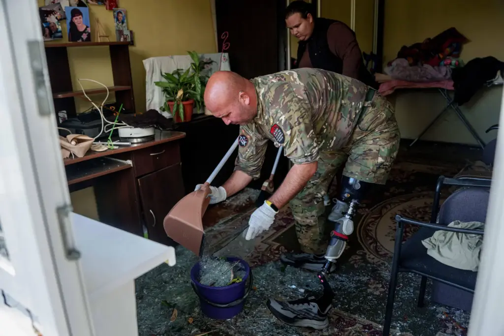 Oleksii, a Ukrainian war veteran, clears broken glass inside an...