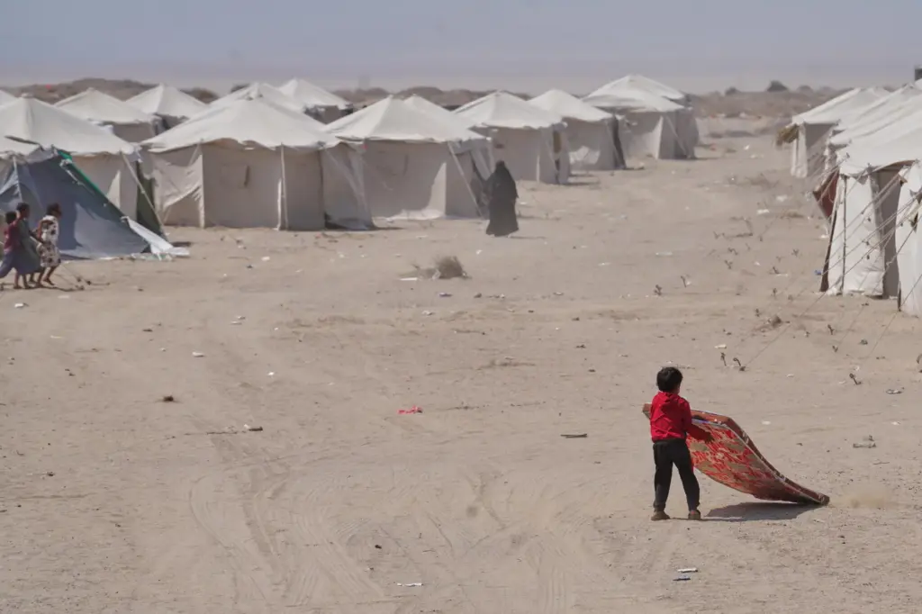 A displaced Yemeni pulls his mattress at Al-Firdaws camp in...
