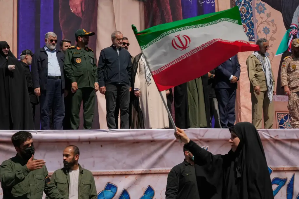 Iranian President Masoud Pezeshkian and other officials watch as a woman waves an Iranian flag.