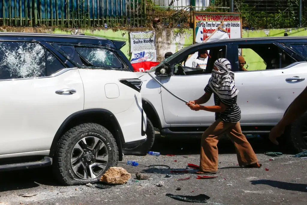 A man attacks a vehicle from an opposing group outside...