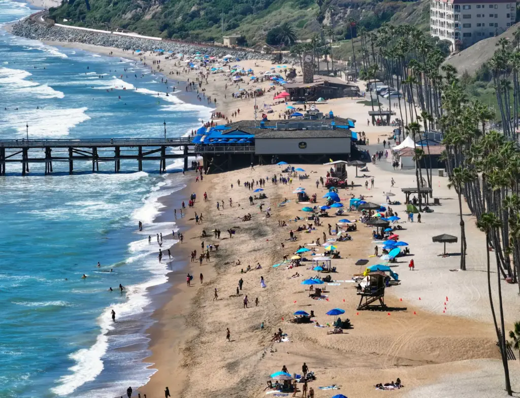 Beach-goers flock to the sand near the pier in San...