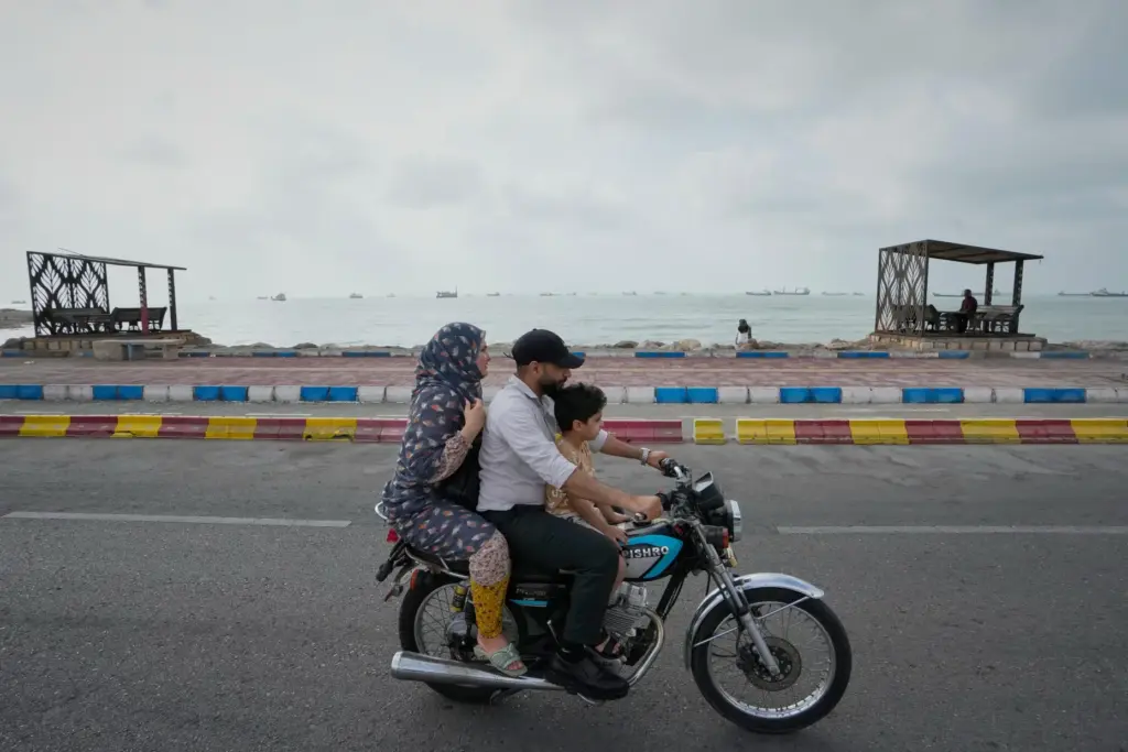 A man, woman and boy ride a motorcycle near the Strait of Hormuz.