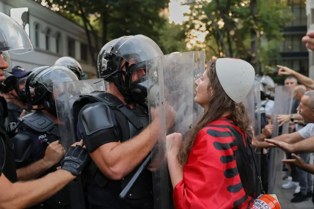 A woman draped in an Albanian flag clashes with police...
