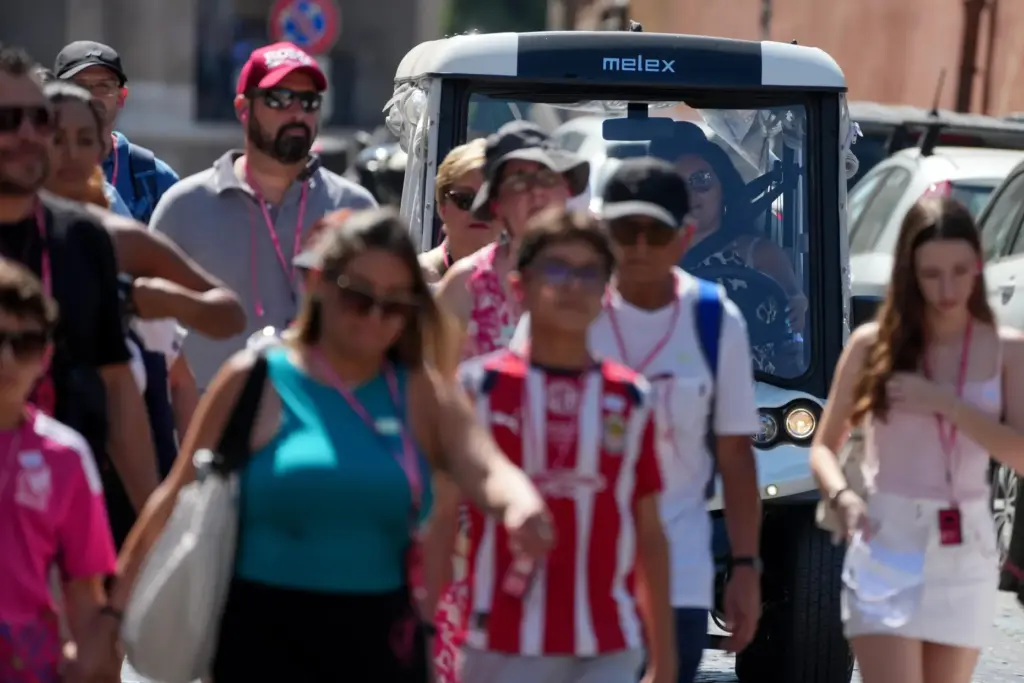 A golf cart makes its way through crowds of tourists.