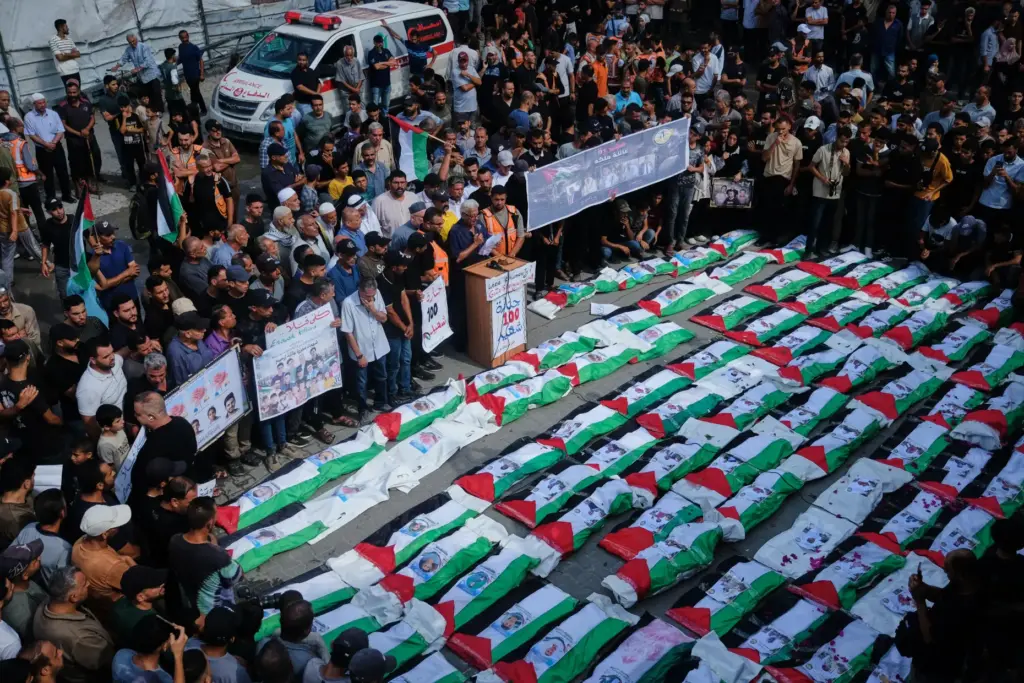 Mourners gather around the flag-draped bodies of Palestinians killed in...