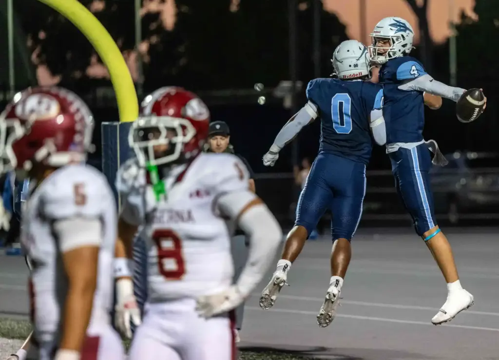 Corona del Mar players celebrate a touchdown by quarterback John...