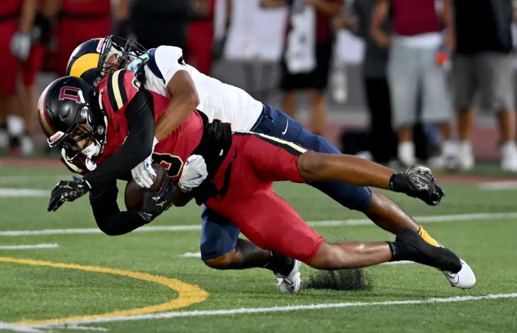 Downey wide receiver Jesus Rios (9) is tackled by Millikan...