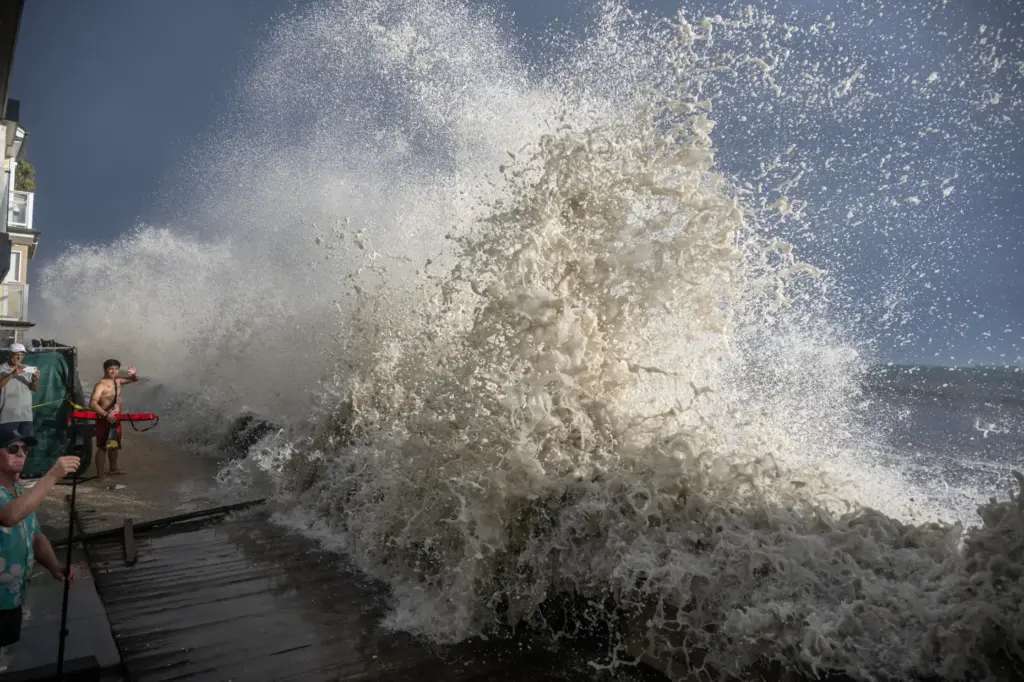 A wave crashes up and over a small retaining wall...