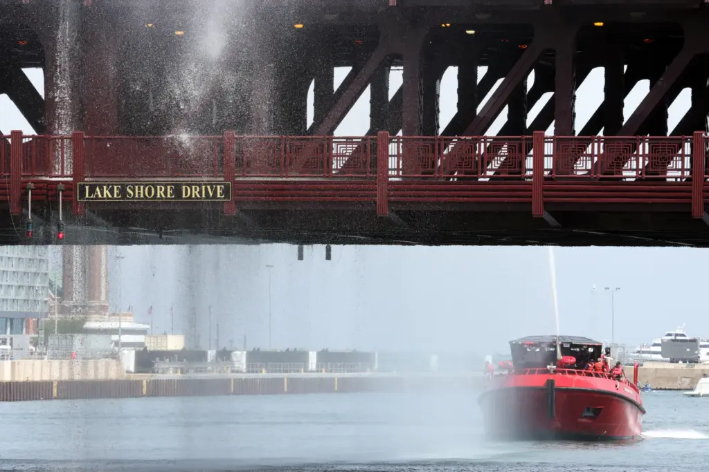 Water pumped by a Chicago Fire Department boat flows down...