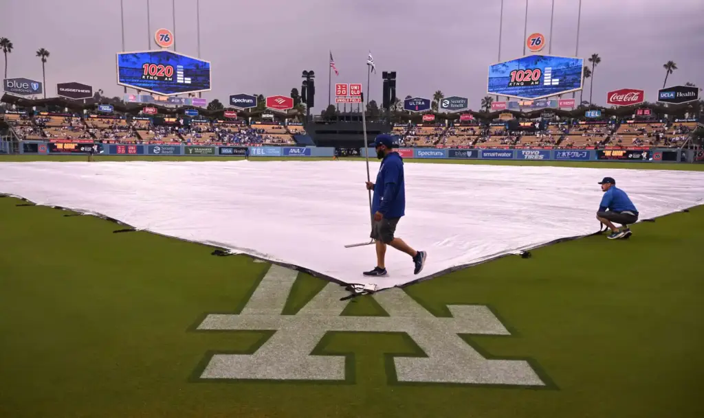 The Dodgers grounds crew works to clear water from the...