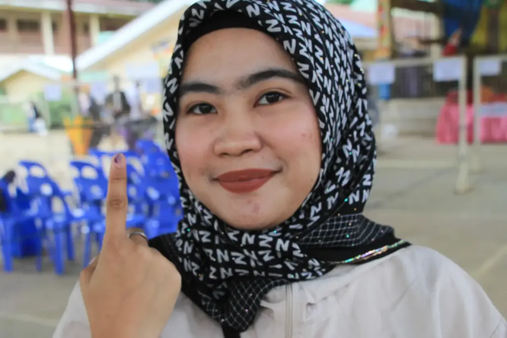 A Muslim woman voter shows the indelible ink on her...