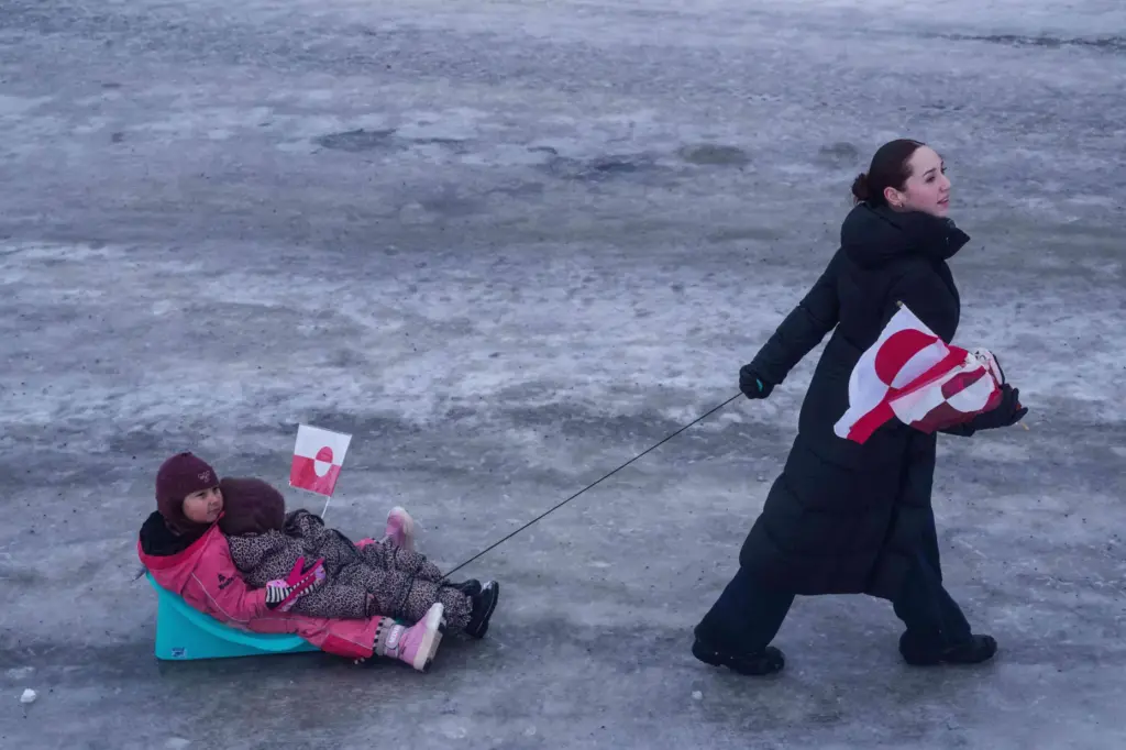FILE – A woman pulls her children on a sled...