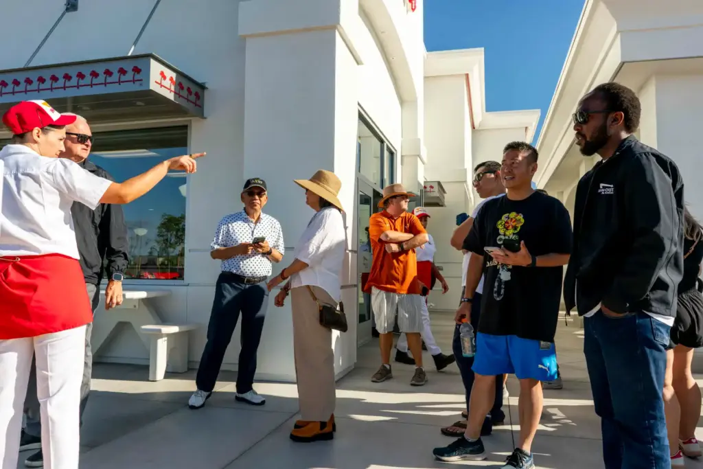 Groups of people wait outside the side entrance of In-N-Out...