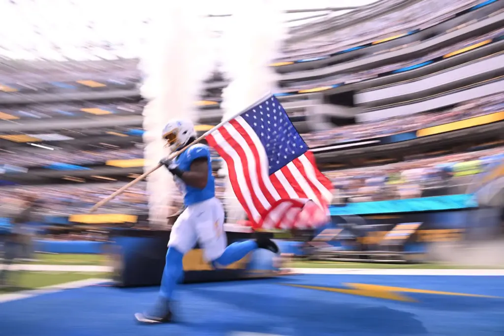 Chargers players enter the field carrying the American flag prior...