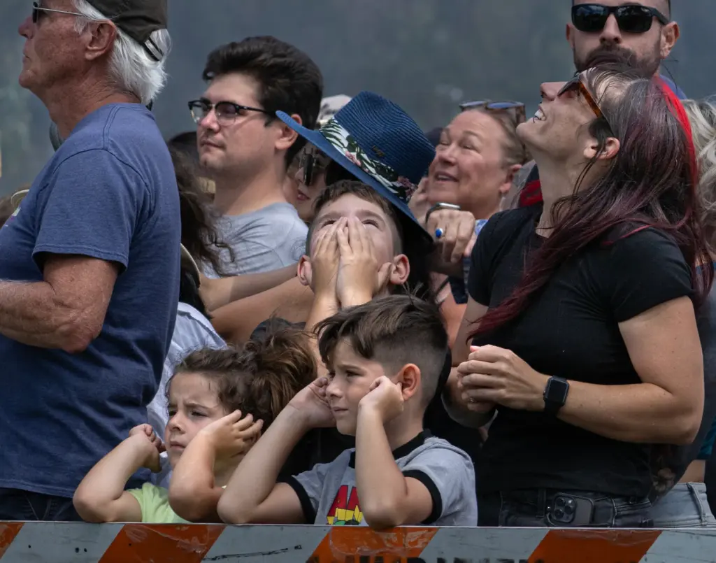 Spectators look skyward while others cover their ears as cannons...