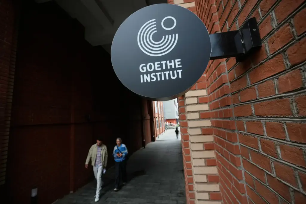 People walk past a street sign of the Goethe-Institut.