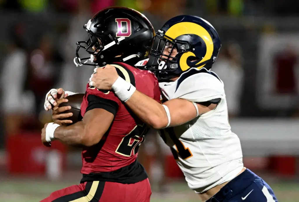 Downey running back Max Acosta (26) is tackled by Millikan...