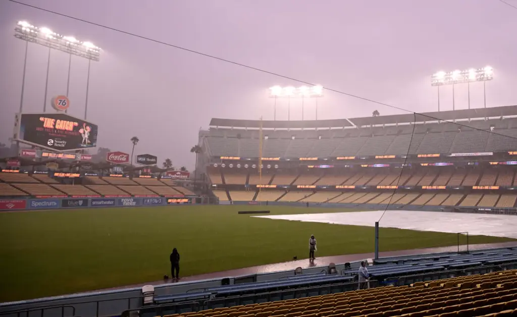 Dodgers security officers stand on the field in the rain...