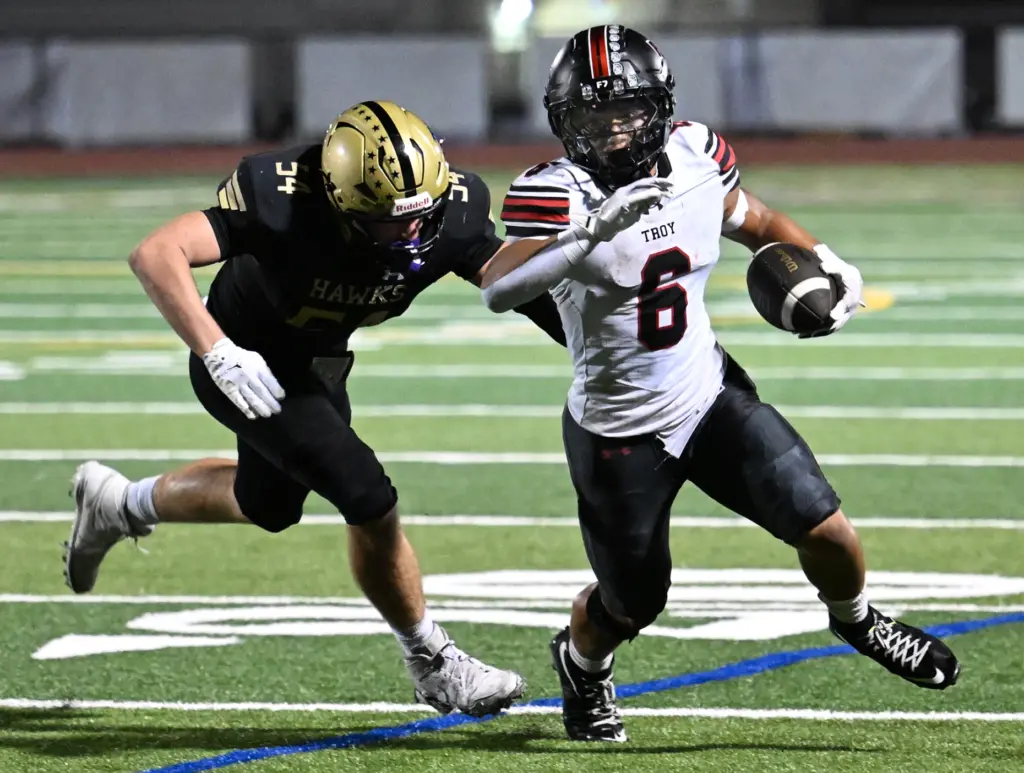 Riley Billington #6 of Troy runs from Matix Wood #54...