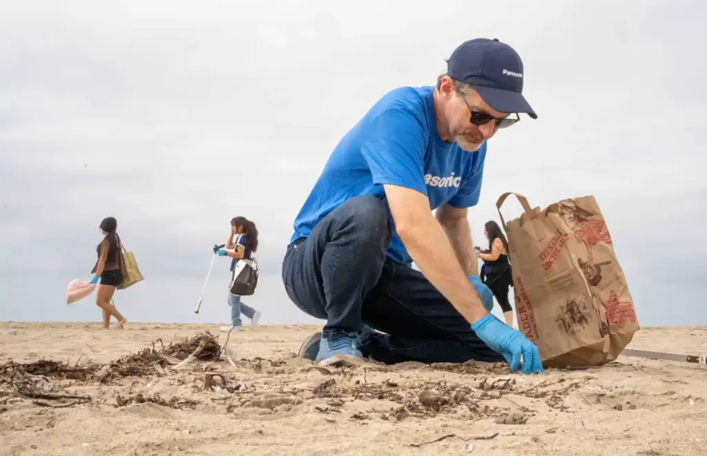 Travis Morgan searches the sand for trash during a company...