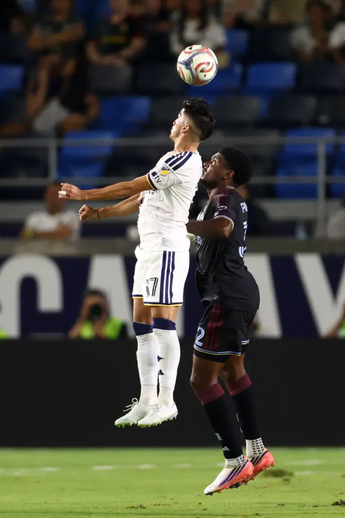 Galaxy midfielder Pablo Ruiz, top, heads the ball defended by...