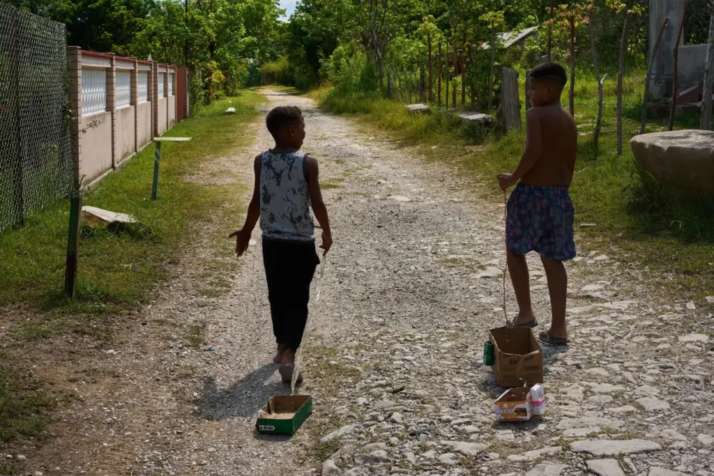 Children drag toys made from cardboard boxes as they walk...