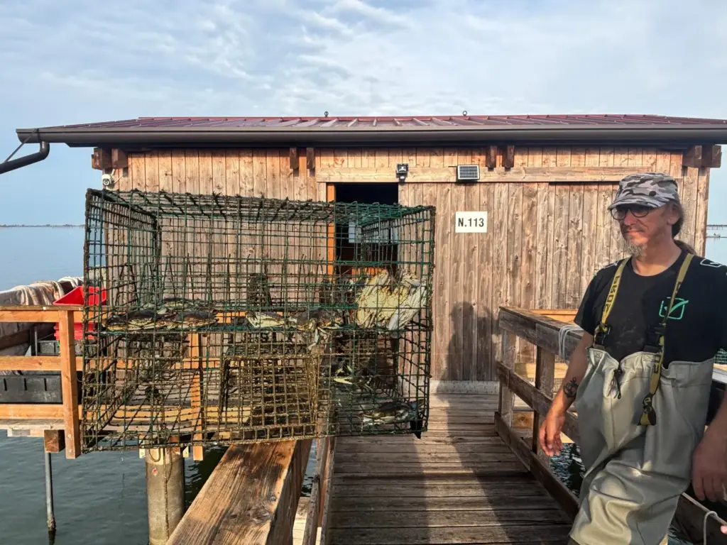Federico Zago poses next to a trap containing blue crabs.