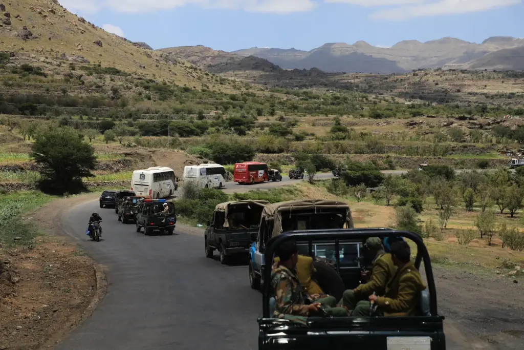 Houthi fighters escort a convoy carrying prisoners freed in Mokha.