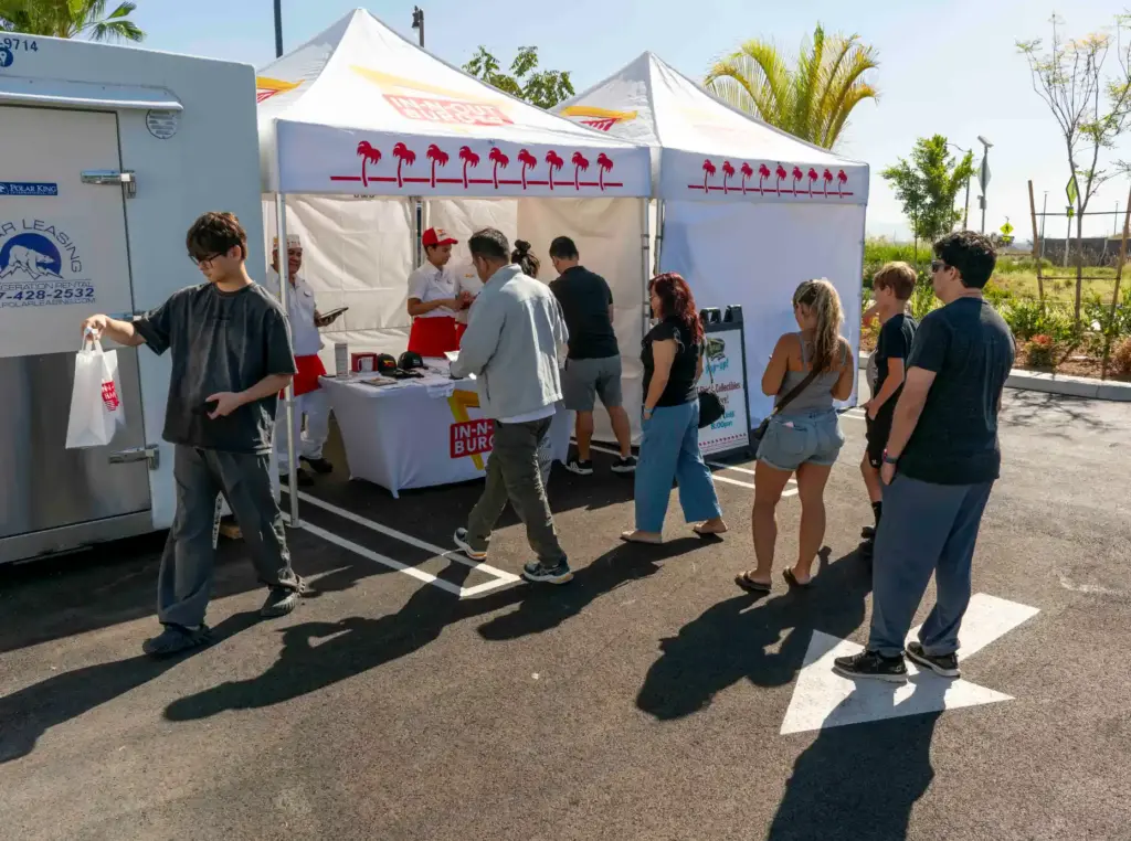 Kevin Xu, left, leaves the In-N-Out merchandise tent with two...